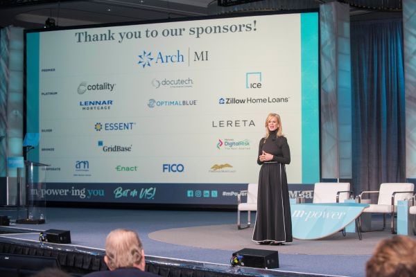 Speaker in front of sponsor sign at mPowering You 2025